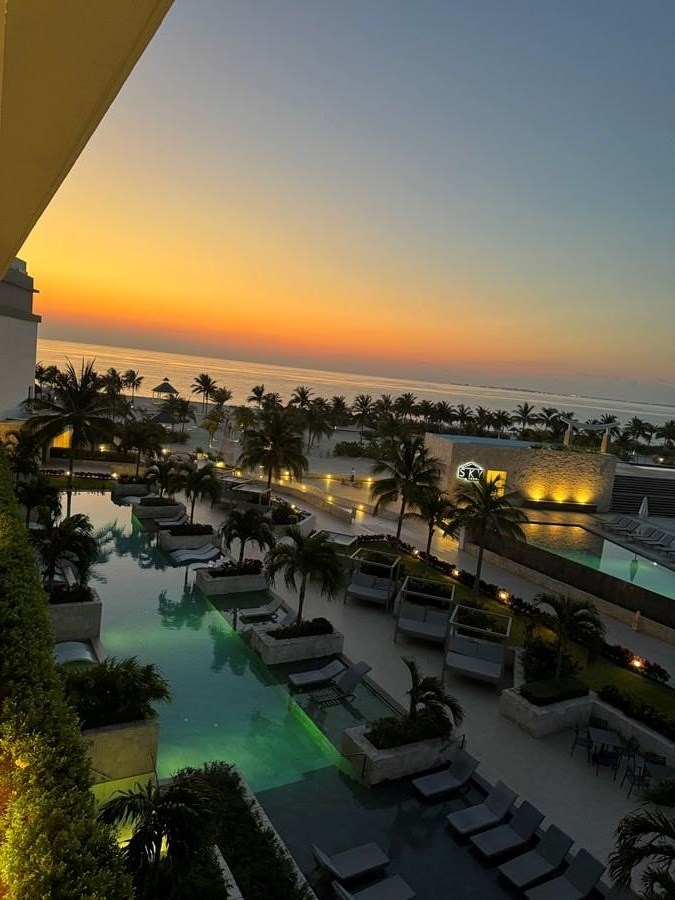 Resort pools and palm trees overlooking the ocean at sunset